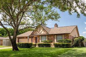 Suburban brick house with trimmed green lawn.